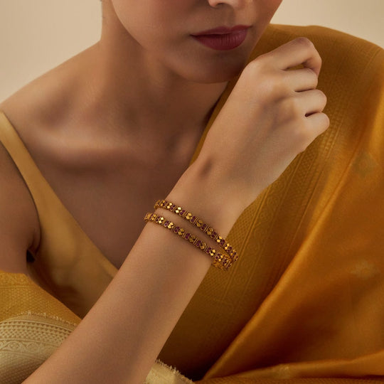 Model wearing antique gold-tone bangles with ruby stones, paired with a sari.