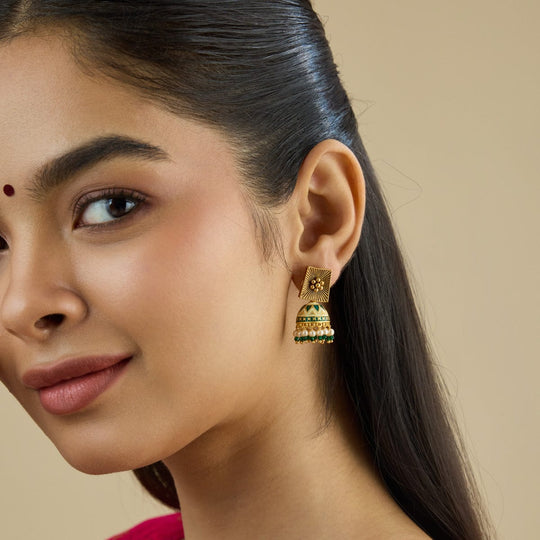 Antique temple jhumka earring with ruby-red stones worn by a model.