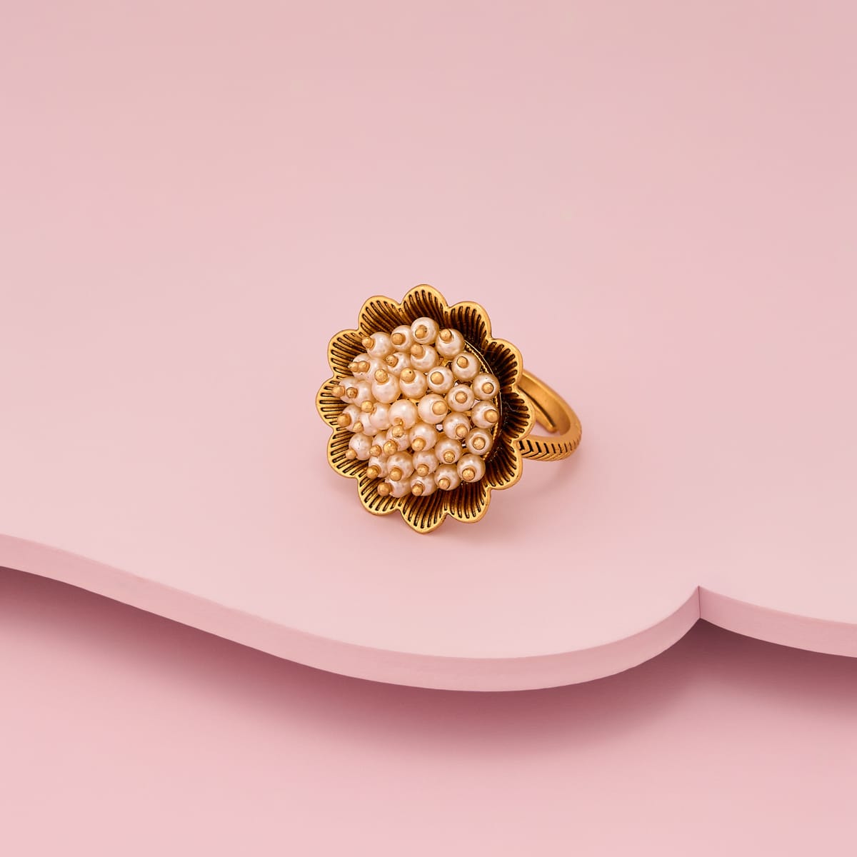 Antique finger ring with pearl-like cluster on gold-tone base, angled view.