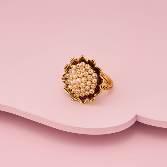 Antique finger ring with pearl-like cluster on gold-tone base, angled view.