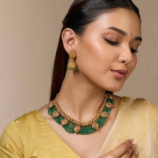 Model wearing antique necklace with green beads and matching earrings.