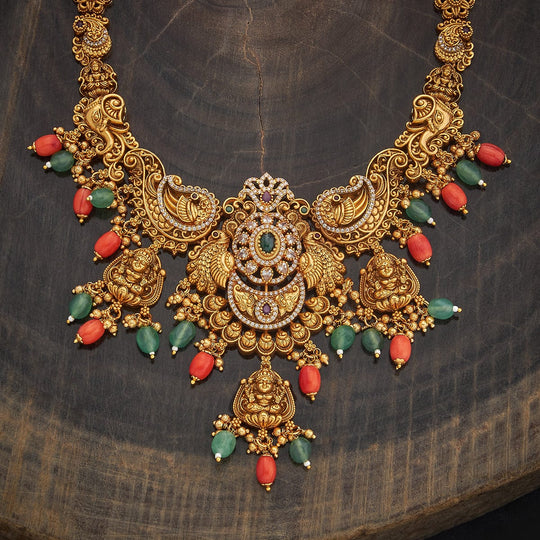 Close-up of antique necklace with intricate peacock motifs and colorful stone drops.