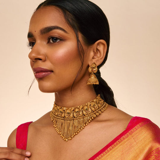 Model wearing antique collar necklace with peacock motif and matching earrings.