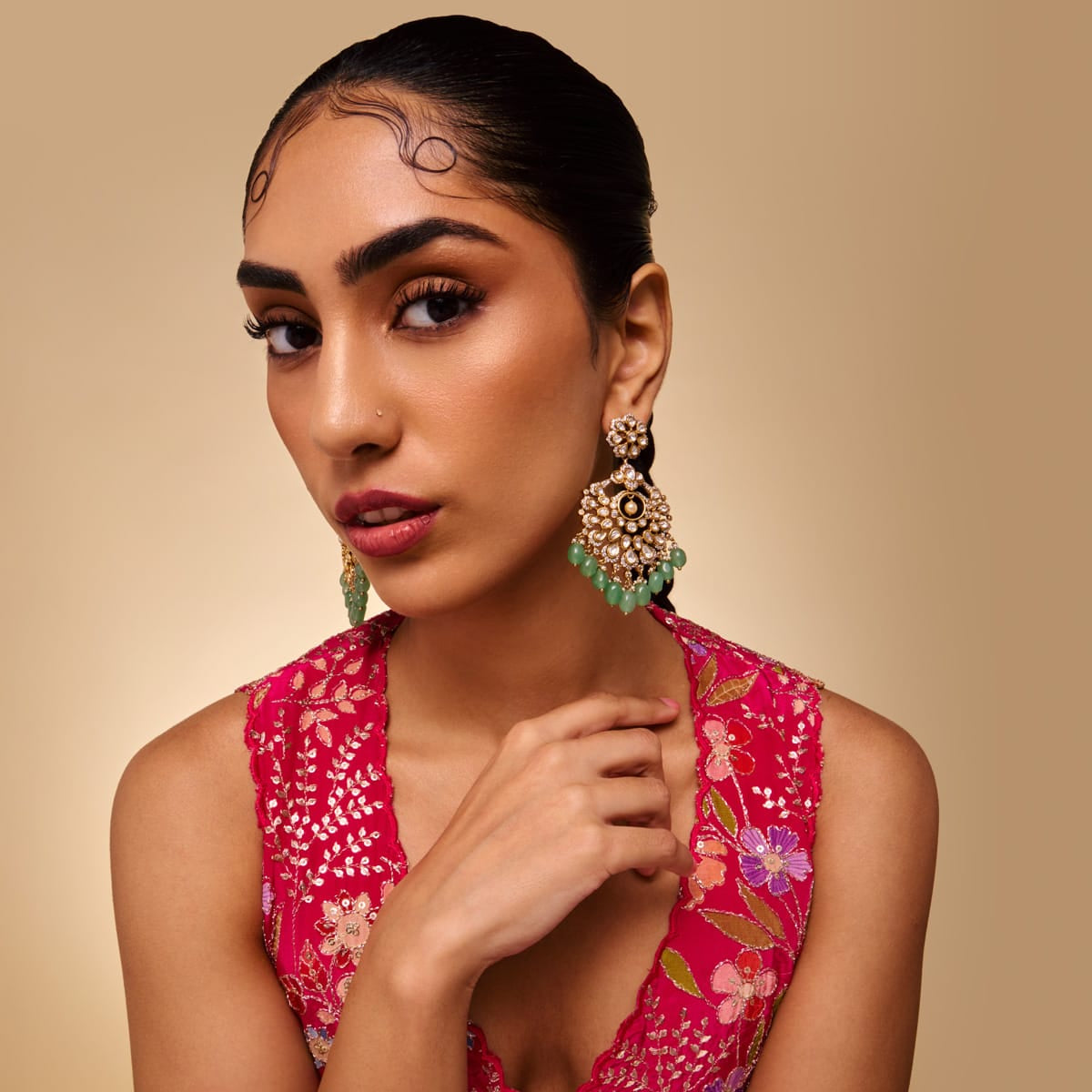 Model wearing Kundan chandbali earrings with green stones, close-up view.