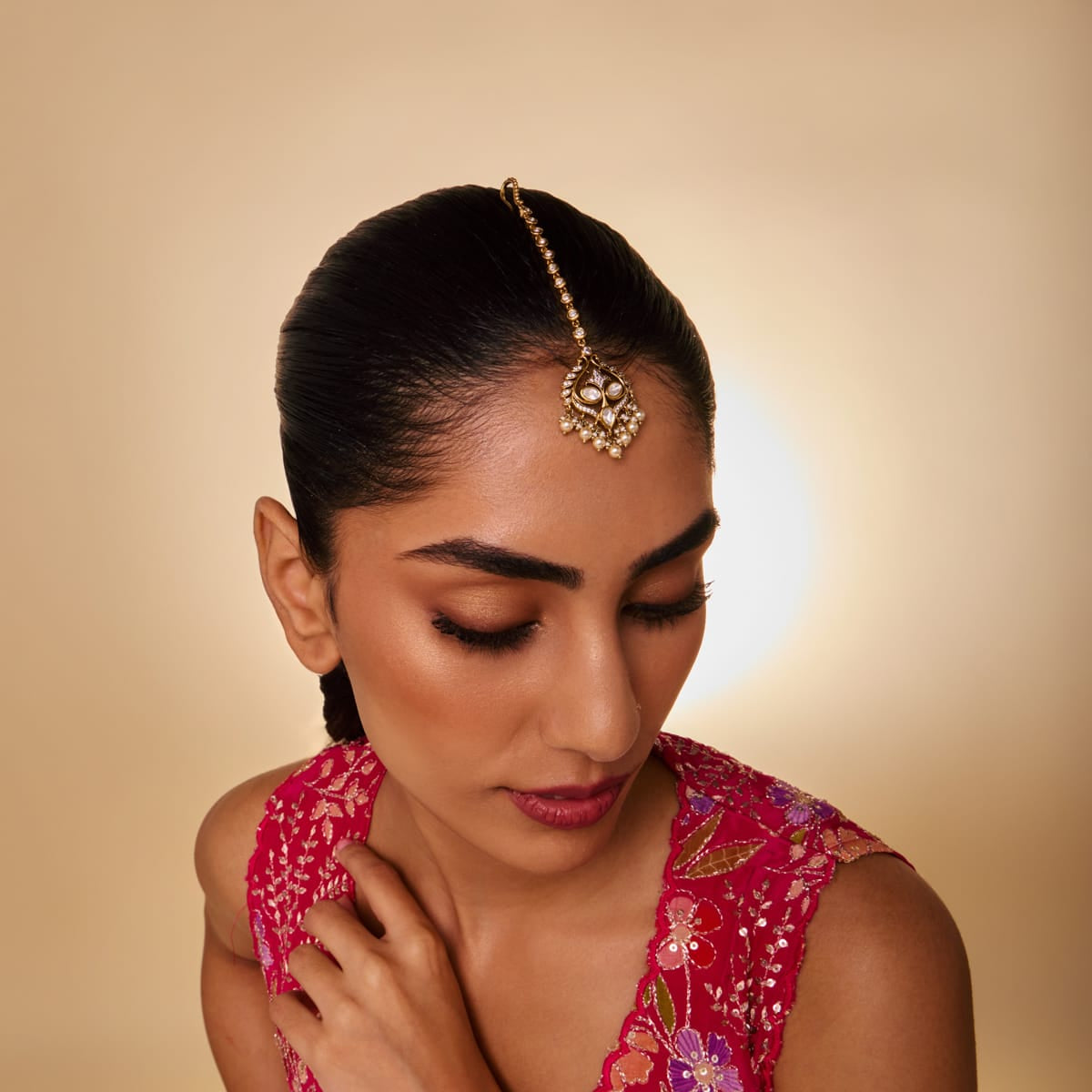Model wearing kundan tikka with pearl drops.