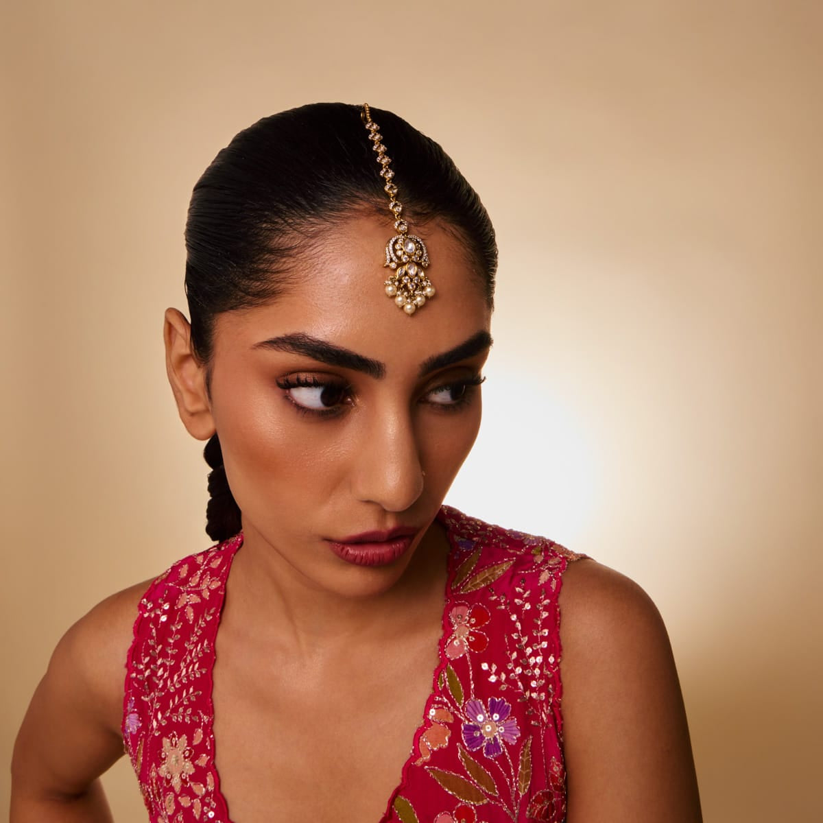 Model wearing a Kundan tikka with white stones and pearls, showcasing traditional style.