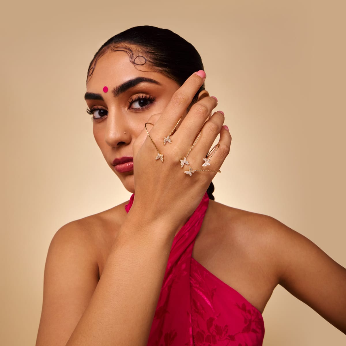 Model wearing gold-tone palm cuff with butterfly motifs and white stones.