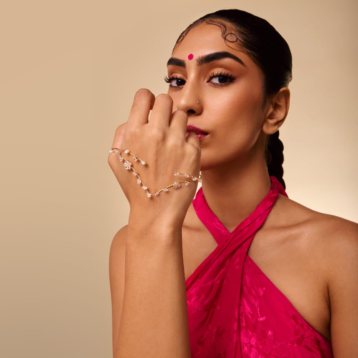 Gold-tone palm cuff with clear stones, worn by a model in red attire.