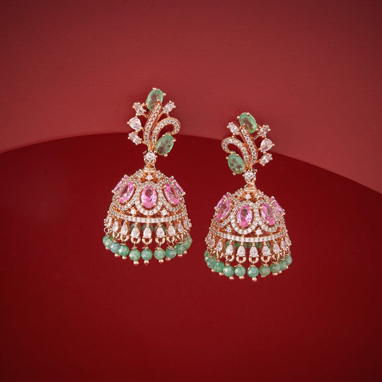 Gold-tone zircon jhumka earrings with green and pink stones, on red background.