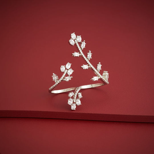 Silver-tone zircon two finger ring with clear stones, linear design, on red surface.