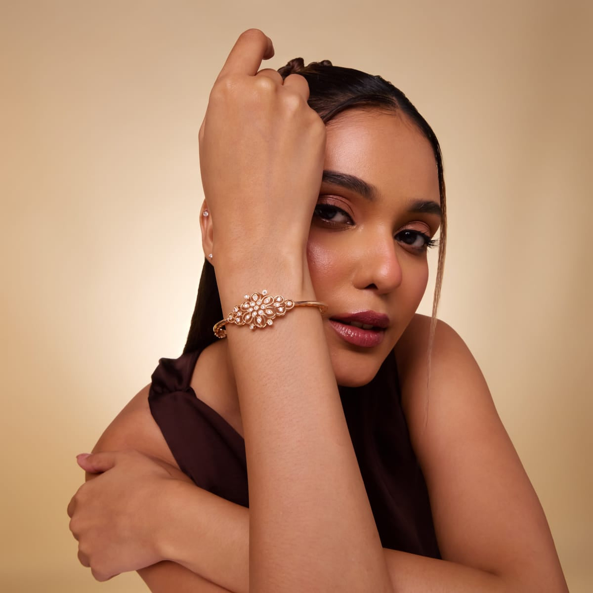 Zircon kada with clear stones, gold polish, worn by a model on the wrist.