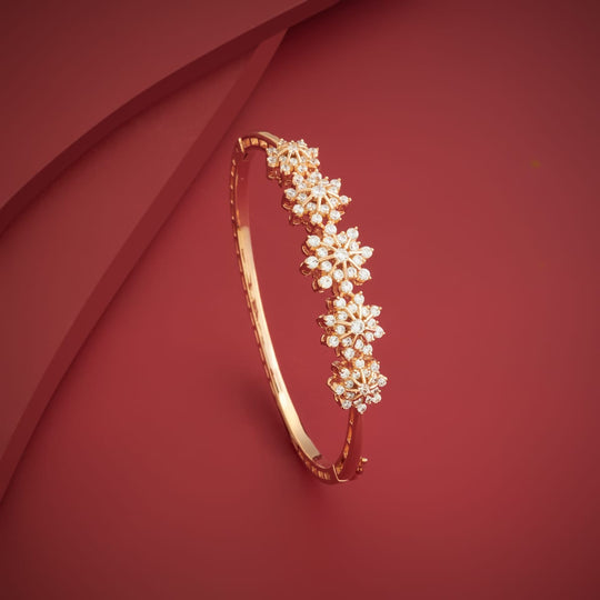 Gold-tone zircon cluster kada on red background, angled view.