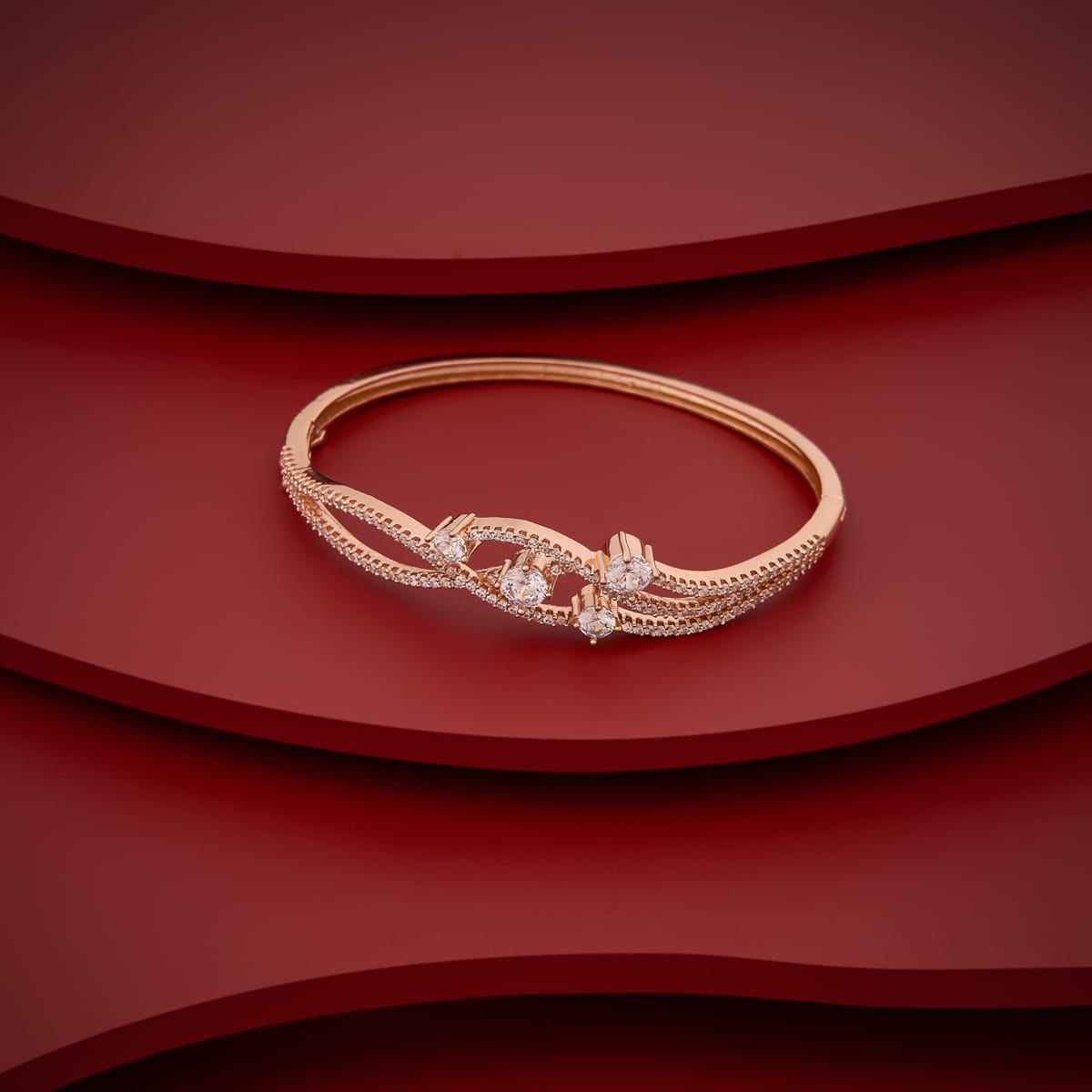 Gold-tone zircon kada with white stones, displayed on a red background.