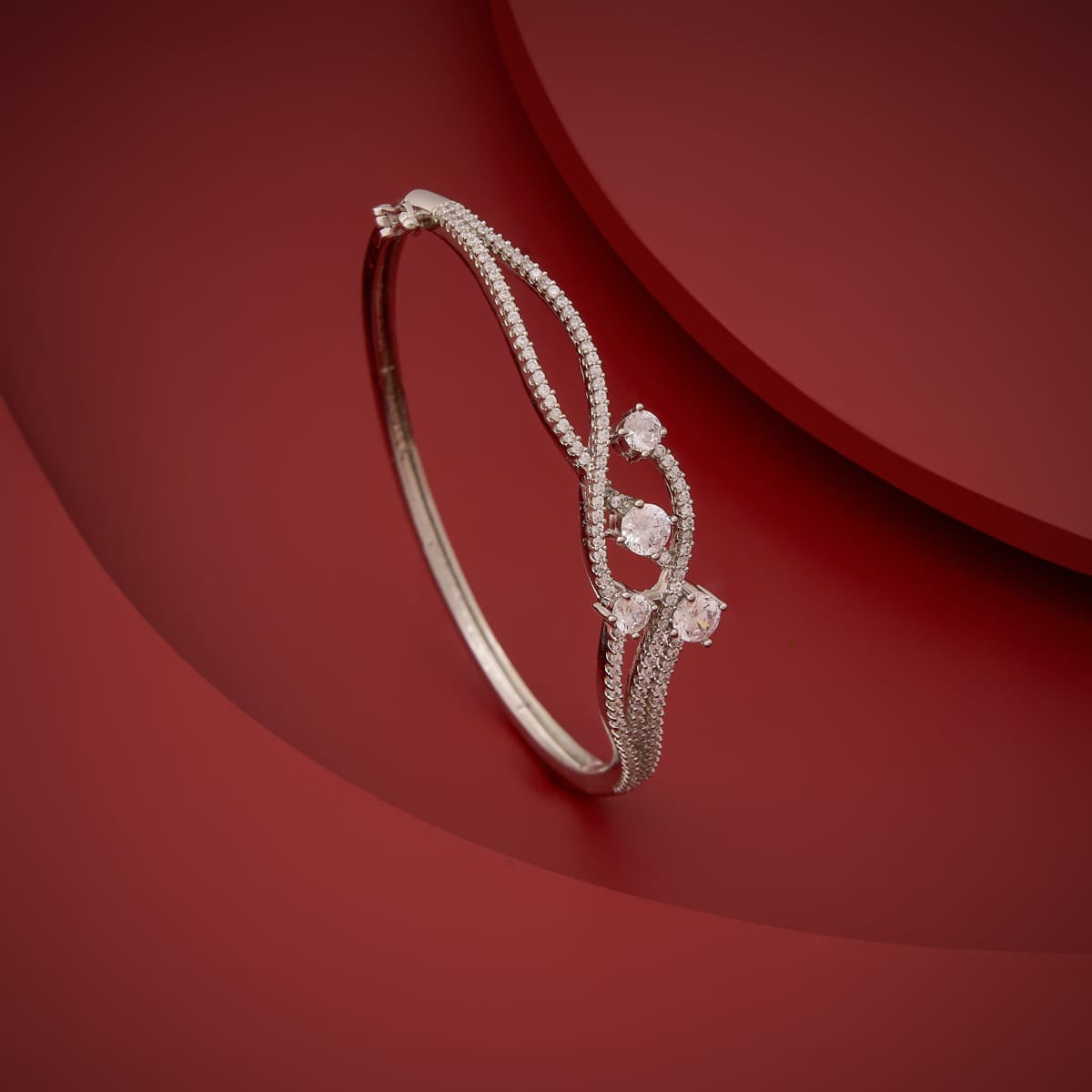 Silver-tone zircon kada with white stones, displayed on a red background.