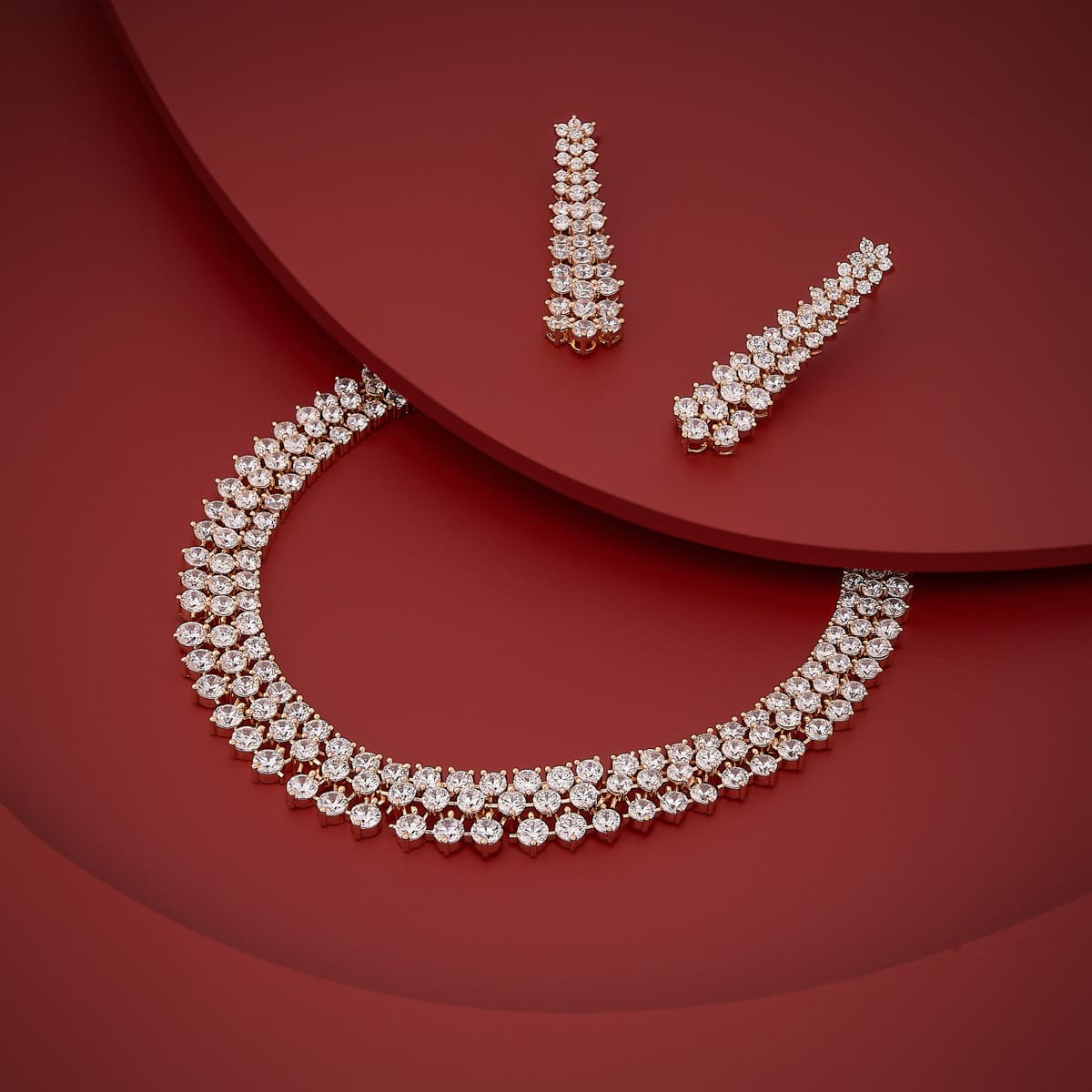 Gold-tone zircon necklace set with white stones on a red background.