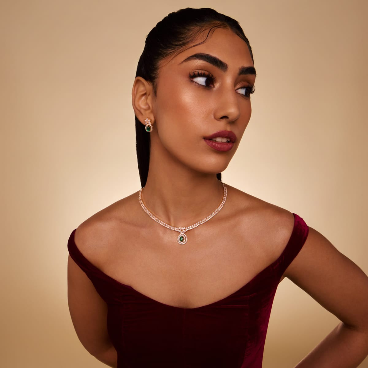 Model wearing zircon necklace with emerald-green pendant and matching earrings.