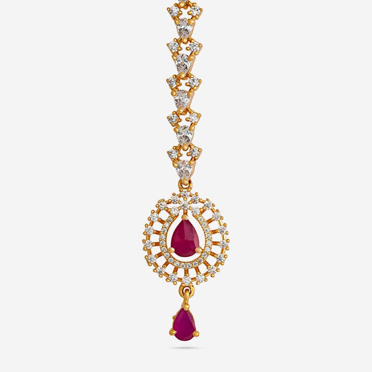 Close-up of gold polish zircon tikka with ruby-red stones, showing floral motif.