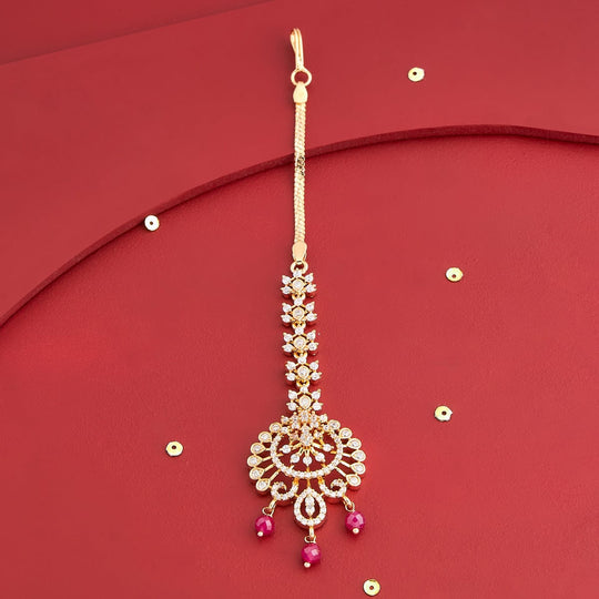 Gold polish zircon tikka with ruby drops on red background, floral motif.
